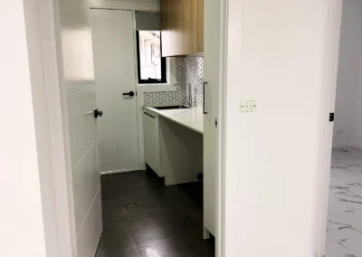Narrow laundry room with dark floor tiles