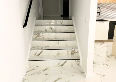 A staircase with white marble-patterned tiles leads