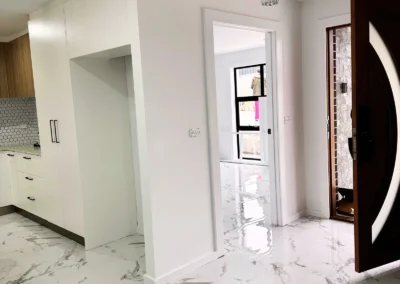 Modern interior with white marble floors and sleek kitchen cabinetry on the left