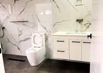 featuring a sleek white toilet and a matching vanity with a white countertop and drawers, exuding a clean