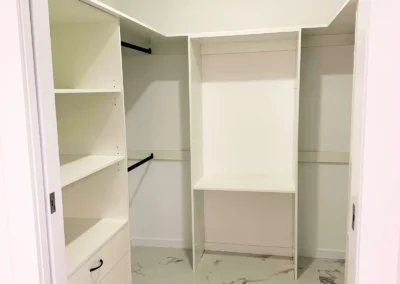 Spacious, white walk-in closet with shelves, drawers, and hanging rods
